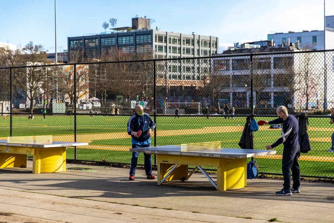 Two men playing ping pong in a park.